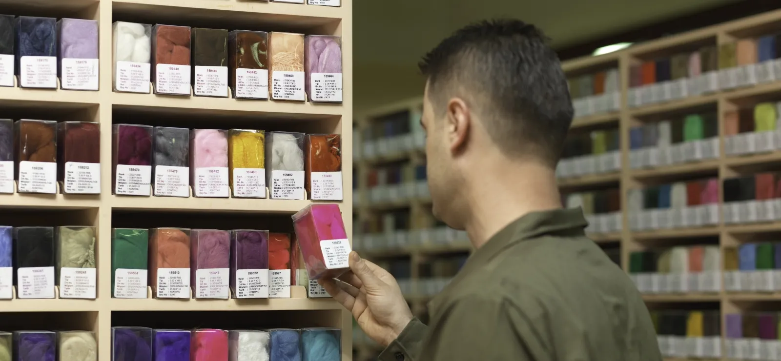 Employee reviewing colorful textile materials for production planning and inventory control