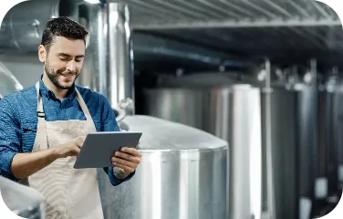 Worker reviews scheduling data and tank telemetry on a tablet.