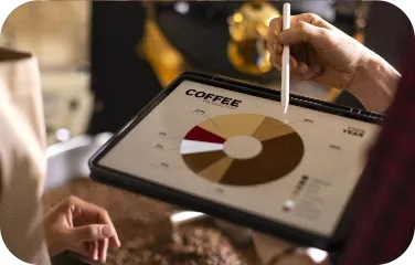 Two people review coffee quality and sales data on a tablet with charts.