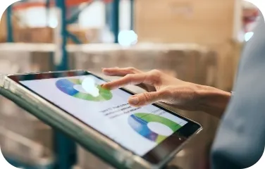 A tablet displays inventory analytics and warehouse performance charts for real-time supply chain management.