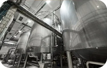 Large stainless steel storage tanks inside an industrial processing plant.