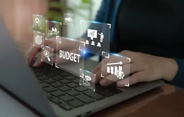 Person typing on laptop with digital budget planning icons