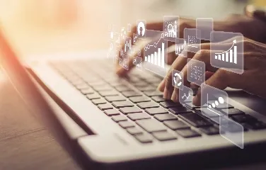 Hands typing on laptop with digital analytics icons