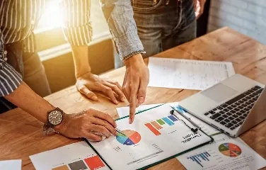 Colleagues pointing at financial report with pie charts
