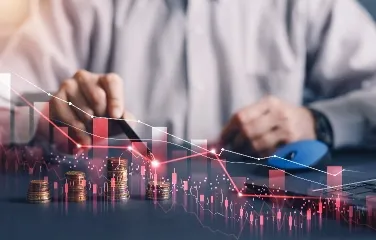 Hand analyzing declining market graph with stacked coins