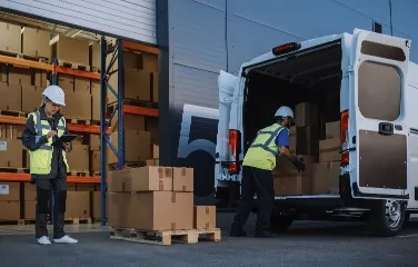 Workers loading delivery van with inventory boxes
