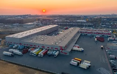 Aerial view of logistics warehouse at sunset with parked trucks