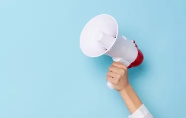 Hand holding megaphone on blue background symbolizing announcement