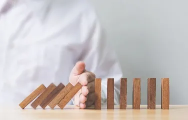 Businessman stopping dominoes symbolizing risk prevention