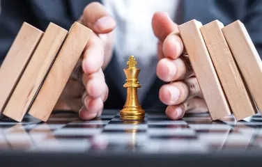Hands protecting a golden chess king symbolizing strategy