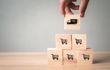 Hand placing delivery icon block on shopping cart pyramid