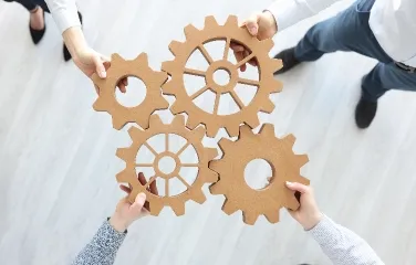Team holding connected gears representing collaboration and process alignment