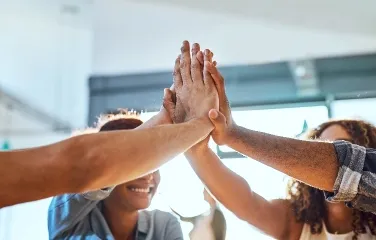 Diverse team giving a group high-five celebrating collaboration