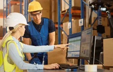 Engineers analyzing data on computer screens in warehouse environment