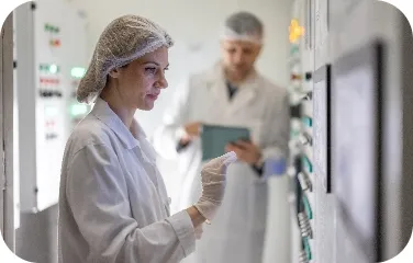 Technician checking controls and recording data in dairy lab.