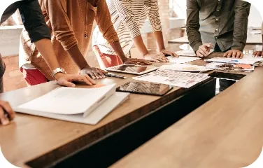 A group of colleagues leaning over documents during a planning meeting.