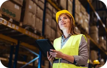 Warehouse staff using a tablet to inspect shelves and record inventory.