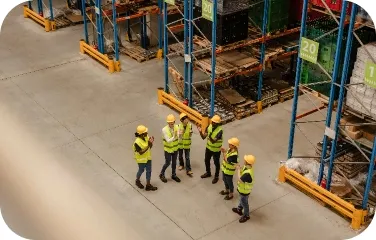 A warehouse team discusses inventory management and supply chain operations in a large storage facility.