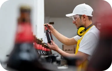 Operator inspects a finished beer bottle for fill, cap, and label quality.