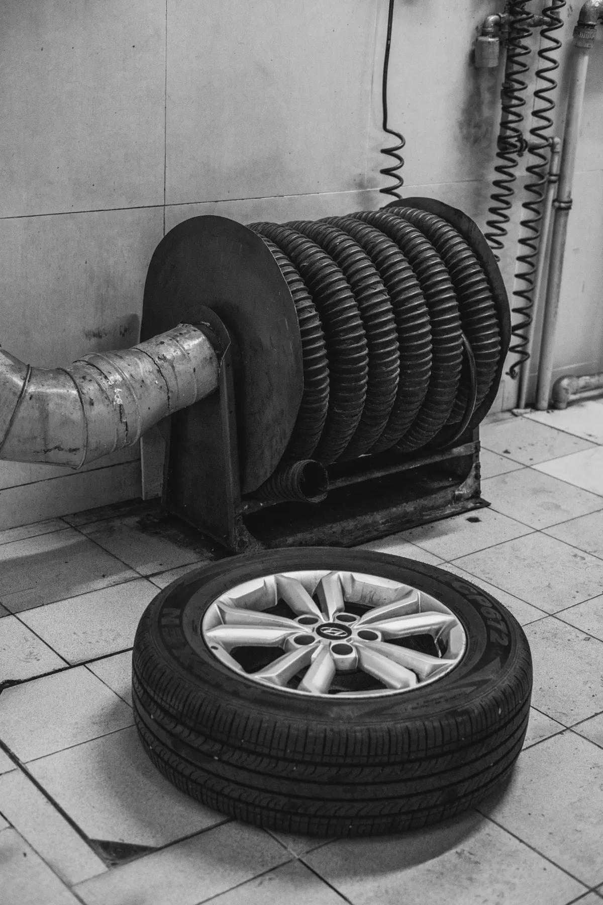 Car tire and coiled air hose in an auto repair workshop, showing industrial tools and maintenance setup