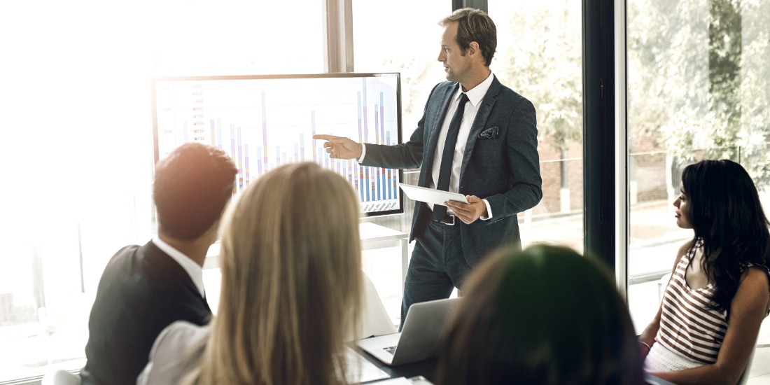 Business professional presenting demand forecasting data during supply chain planning meeting