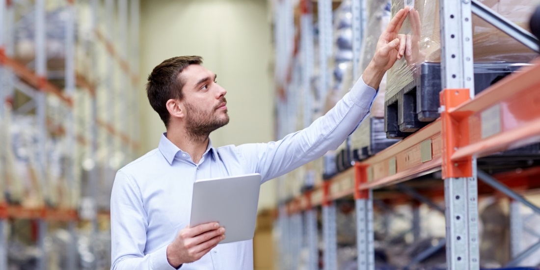 Supply chain manager using tablet to inspect warehouse stock and improve inventory management accuracy