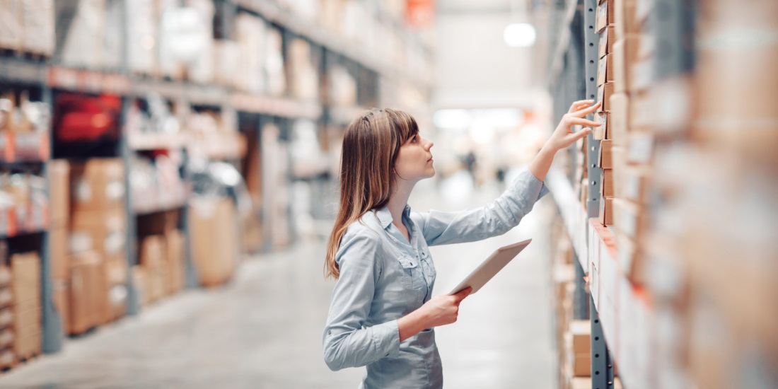 Female warehouse manager using tablet to check inventory levels and improve order management efficiency