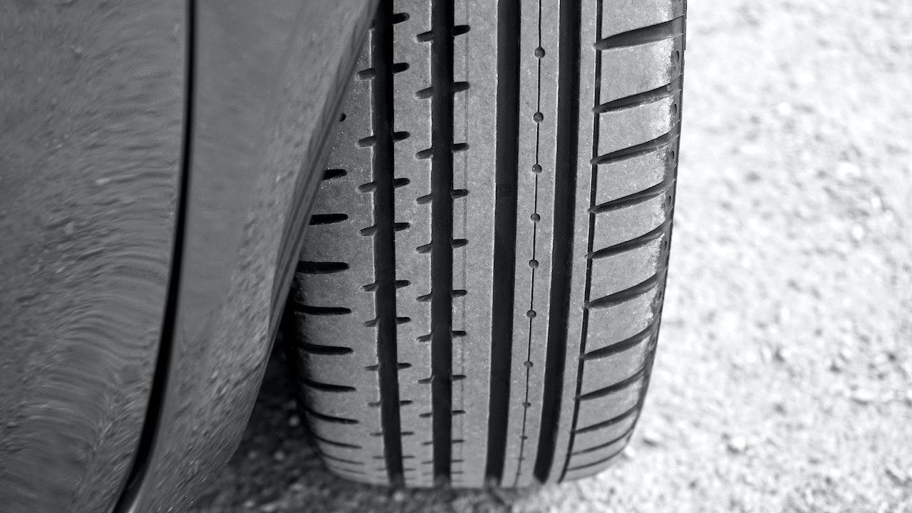 Close-up view of a car tire tread pattern showing rubber texture and wear on the road surface