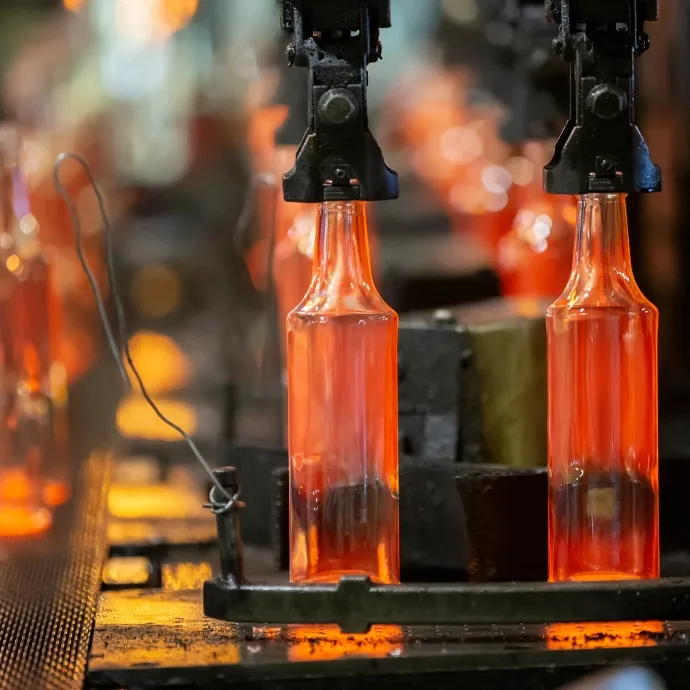 Molten glass bottles being shaped and cooled on an automated glass manufacturing production line