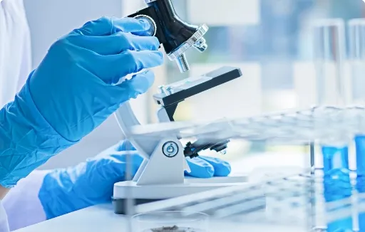 Gloved researcher adjusting microscope during pharmaceutical or life sciences analysis