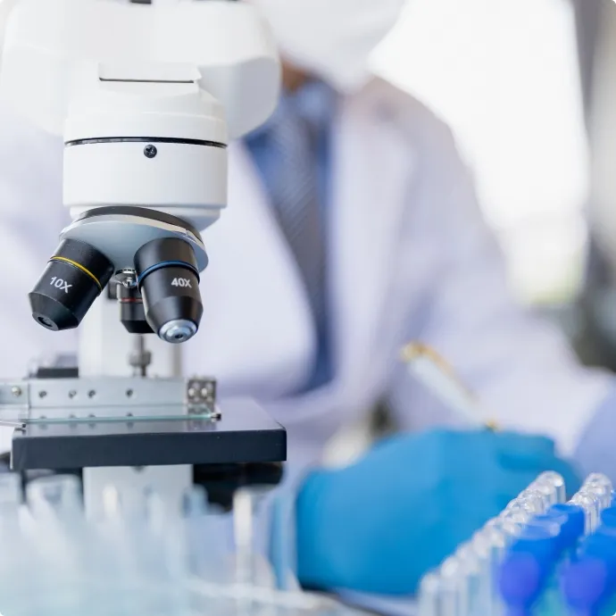 Scientist using microscope in pharmaceutical laboratory for quality testing and research