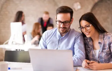 Two professionals collaborating on a laptop, reviewing supply chain optimization strategies